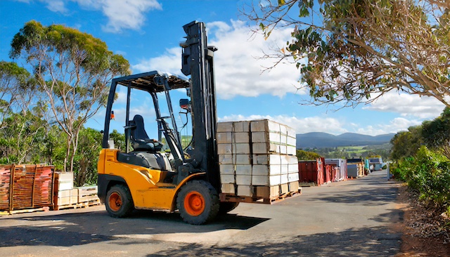 A yellow forklift carrying a pallet of cargo, on an Australian road