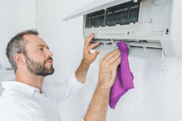 man cleaning a split system air conditioner indoor unit