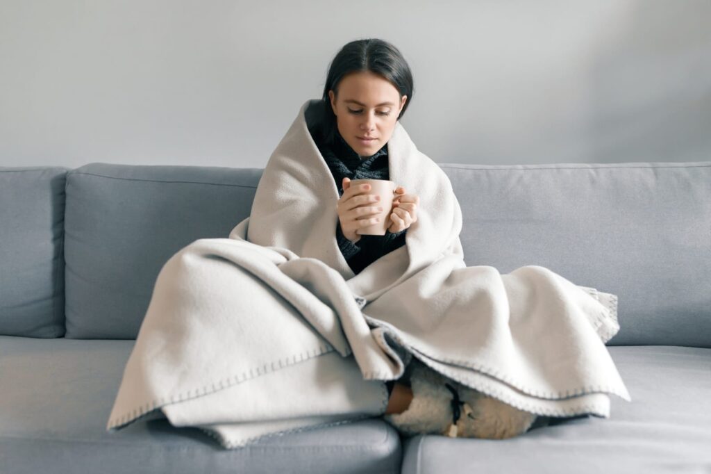 person wrapped in blanket feeling cold in winter