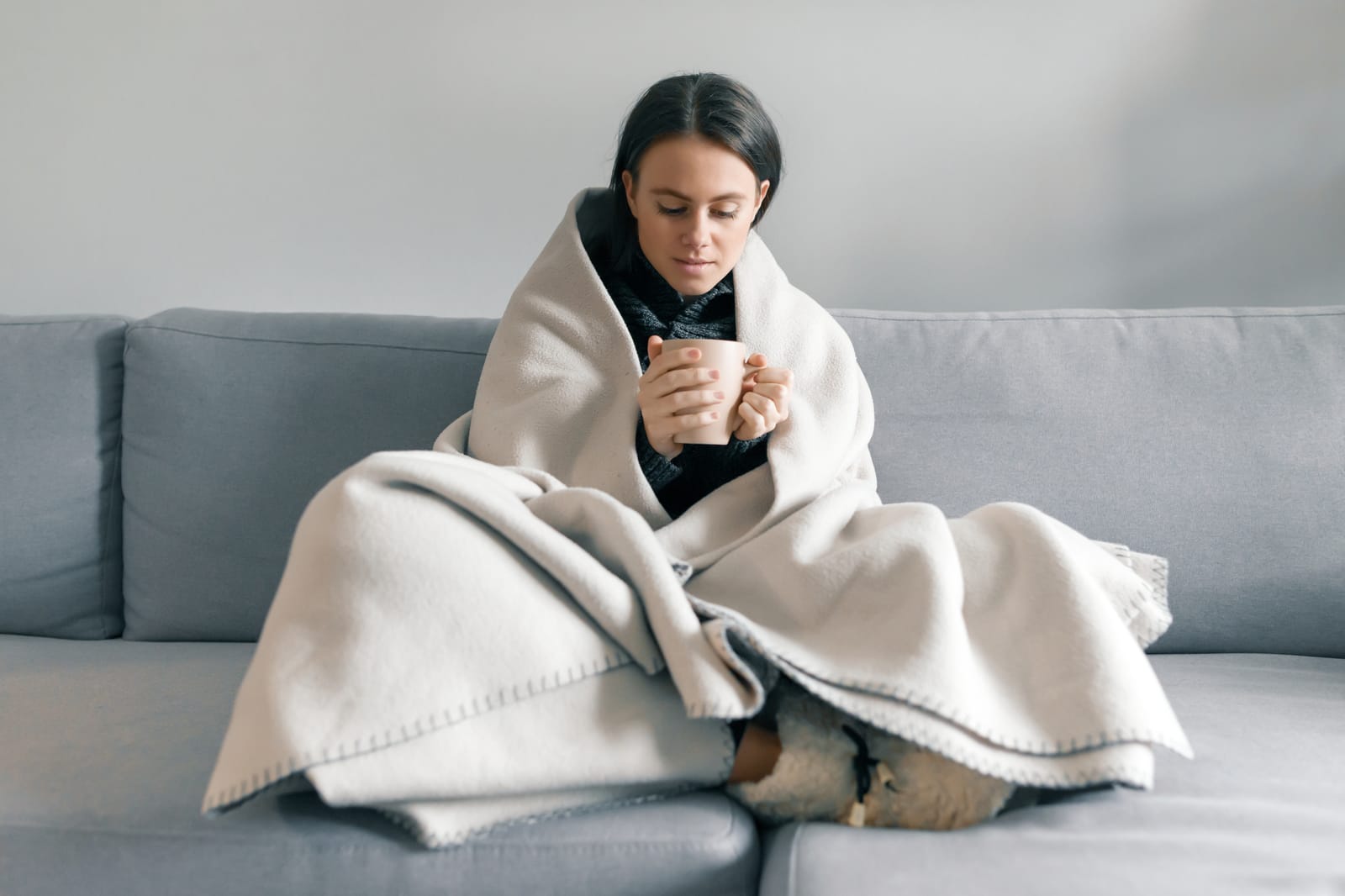 person wrapped in blanket feeling cold in winter